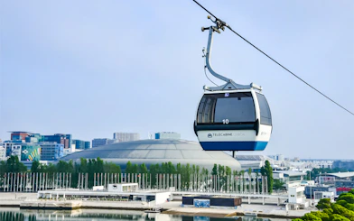 Lisbon cable car over waterfront with cityscape in background.