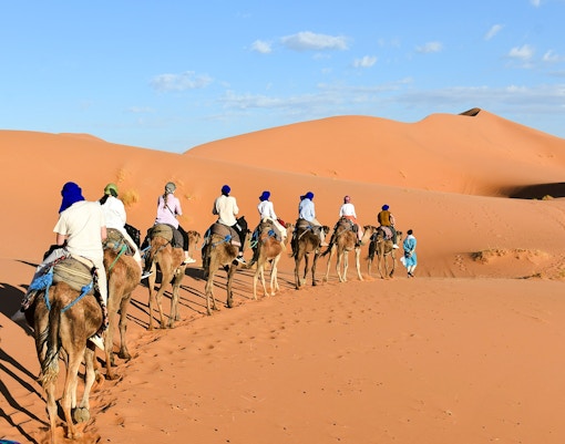 People riding camels through the Agafay Desert dunes.