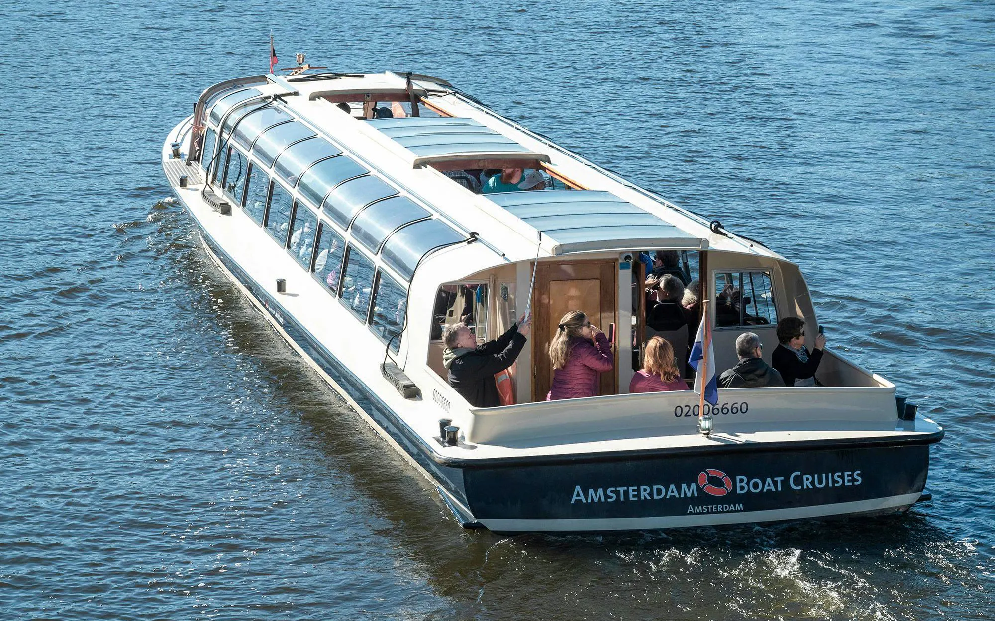 Amsterdam canal cruise boat with passengers enjoying the view.