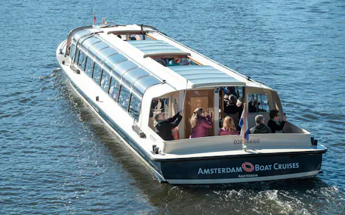 Amsterdam canal cruise boat with passengers enjoying the view.