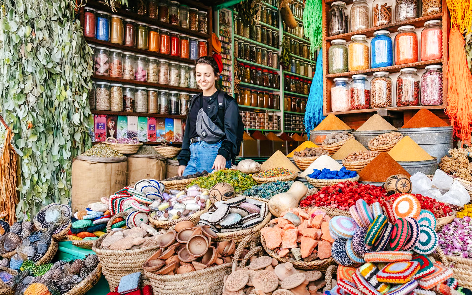 Marrakech souk with colorful spices, jars, and a person exploring the vibrant market.