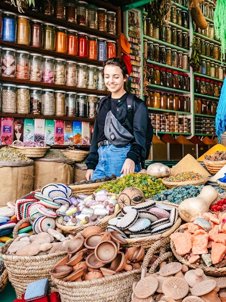 Marrakech souk with colorful spices, jars, and a person exploring the vibrant market.