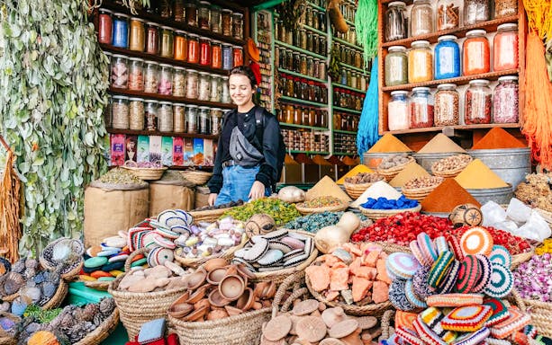Marrakech souk with colorful spices, jars, and a person exploring the vibrant market.