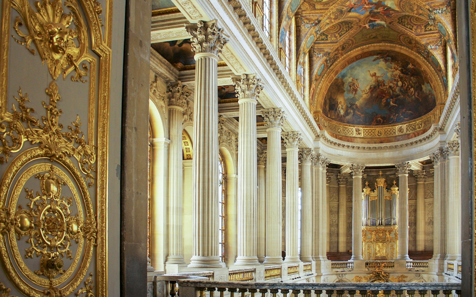Royal Chapel of Versailles upper gallery with ornate ceiling and grand arches.