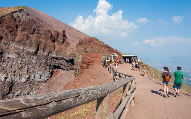 Tourists walking along the crater rim of Mount Vesuvius during a guided day tour from Naples.