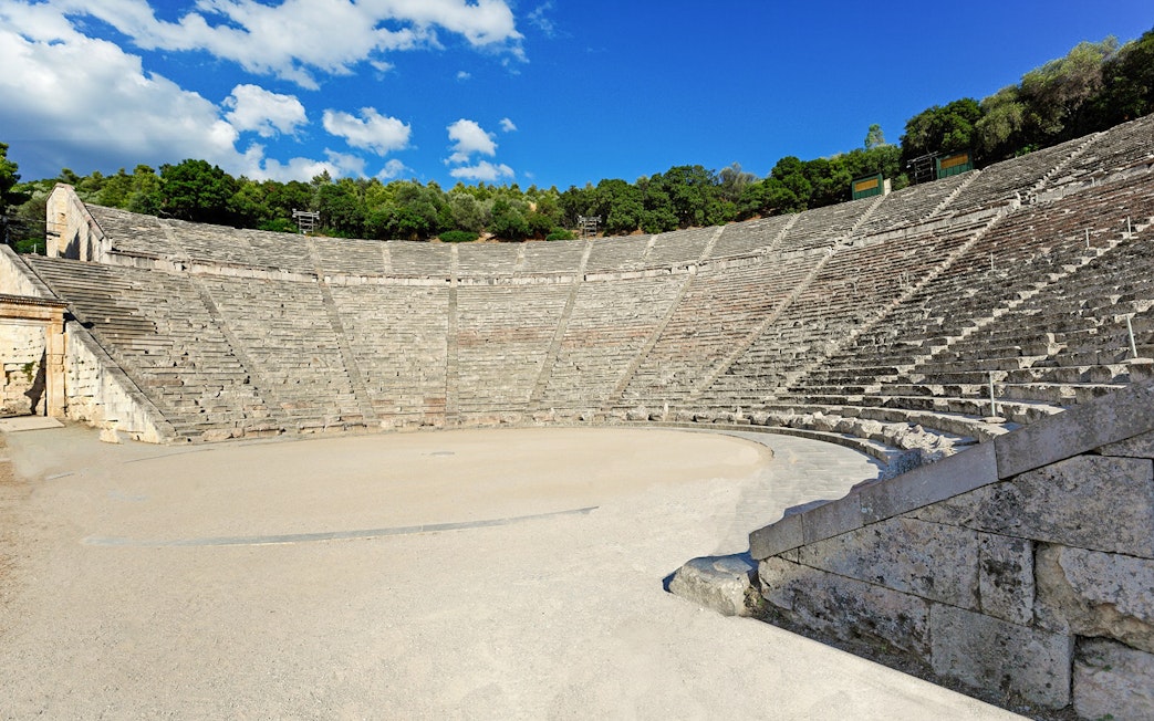 Epidaurus Ancient Theatre with stone seating and stage under a blue sky.