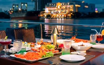 Dinner setup on a cruise with Bangkok skyline in the background.