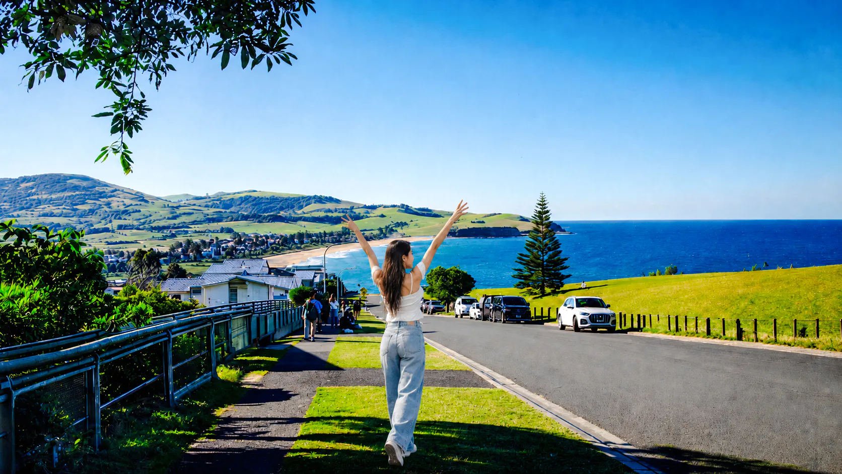 Person enjoying coastal view near Kiama Blowhole, with ocean and hills in the background, Sydney tour.