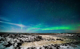 Northern Lights over snowy landscape, Reykjavik, during small-group jeep tour.