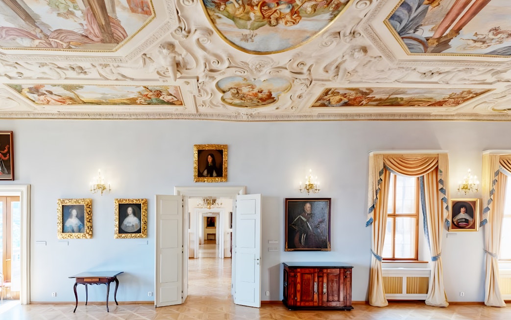 Lobkowicz Palace Museum room with historical paintings and ornate ceiling, Prague.