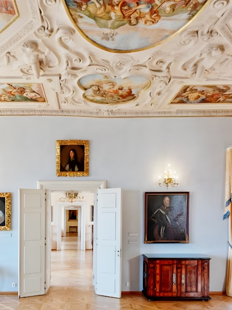 Lobkowicz Palace Museum room with historical paintings and ornate ceiling, Prague.