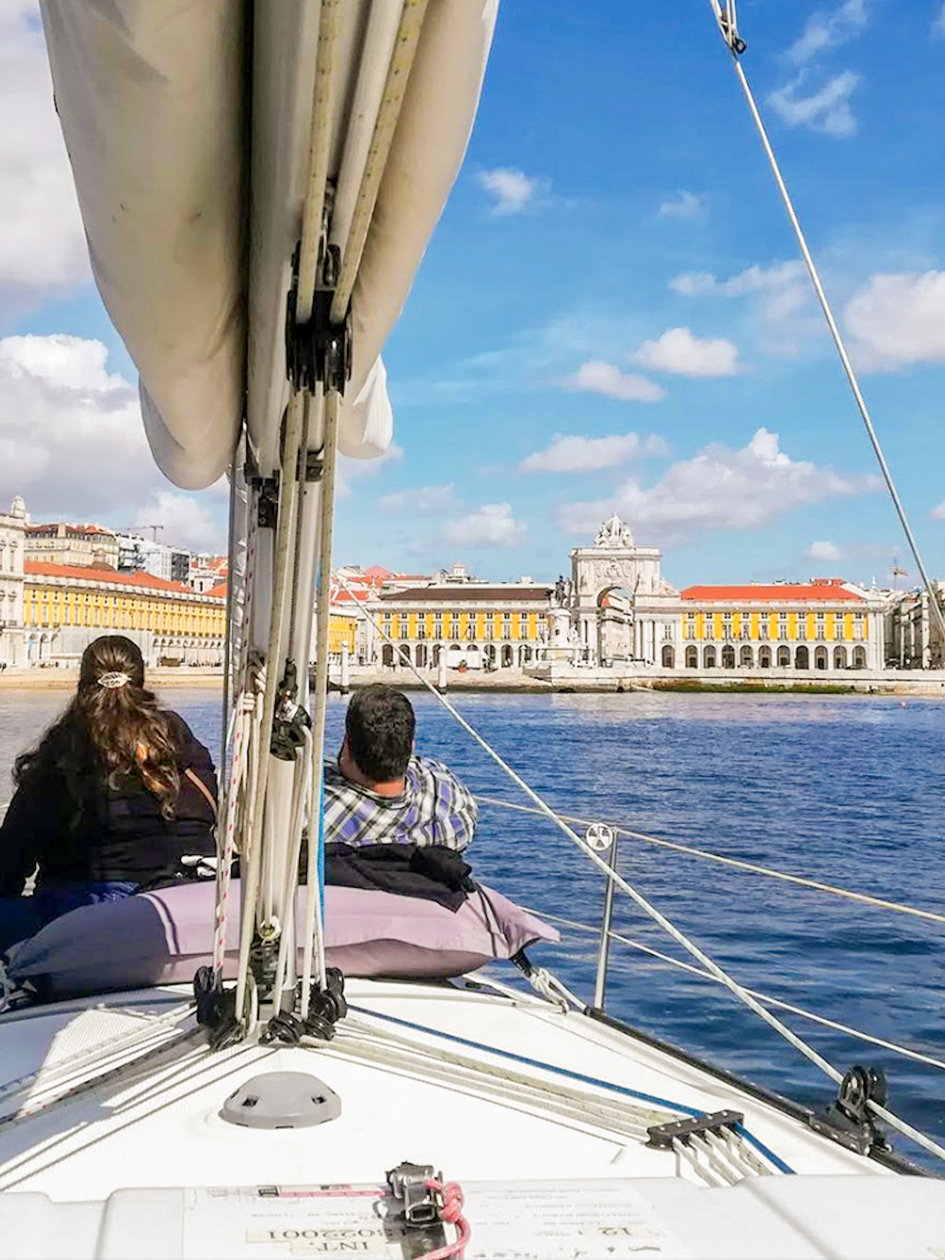 Tourists on a private boat enjoying Lisbon's waterfront view, featuring Praça do Comércio.