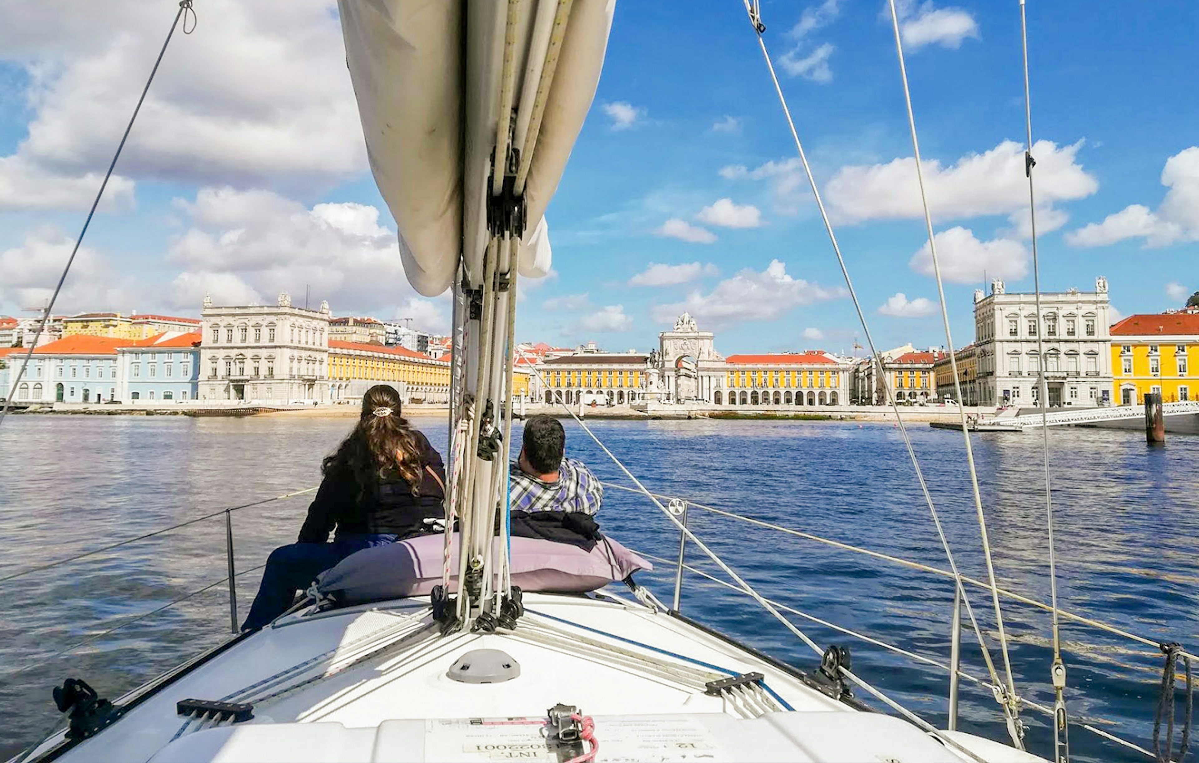 Tourists on a private boat enjoying Lisbon's waterfront view, featuring Praça do Comércio.