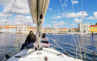 Tourists on a private boat enjoying Lisbon's waterfront view, featuring Praça do Comércio.