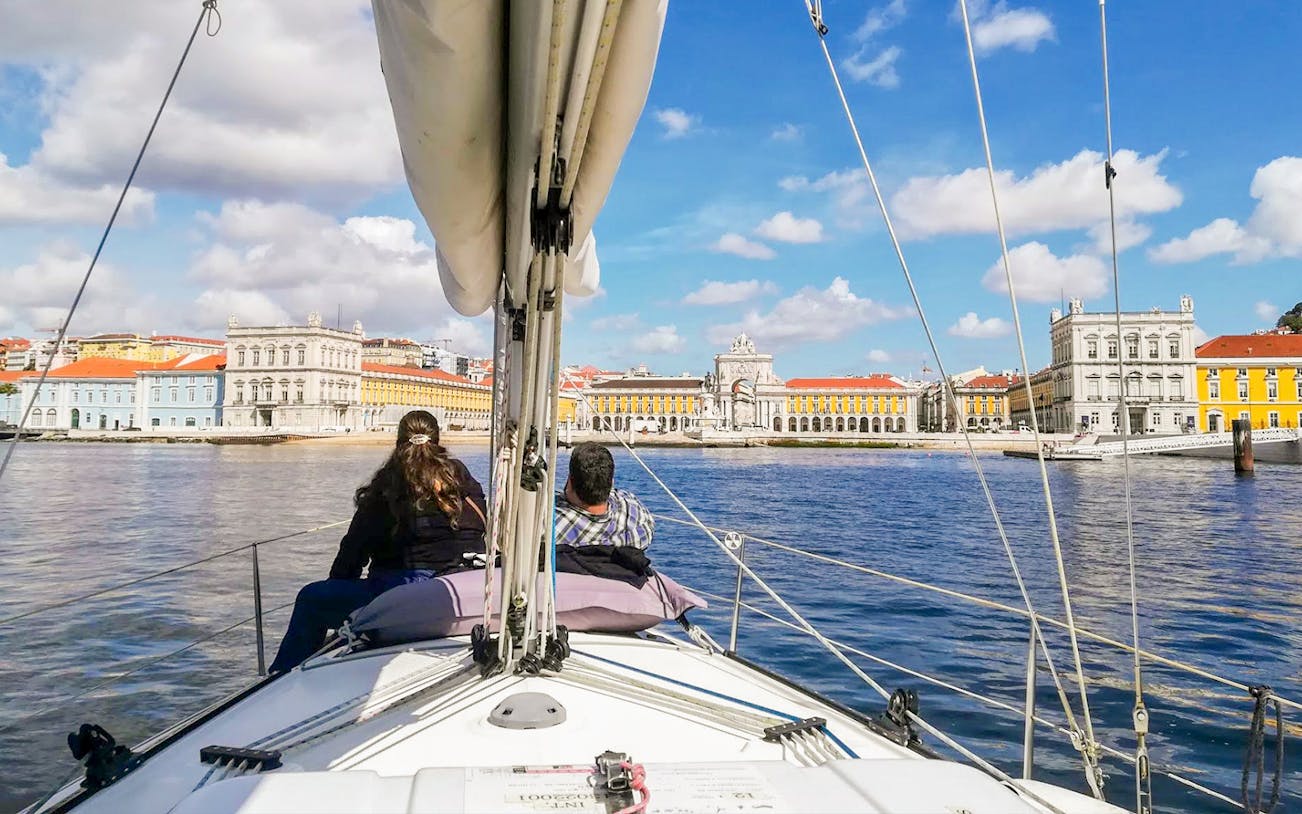 Tourists on a private boat enjoying Lisbon's waterfront view, featuring Praça do Comércio.