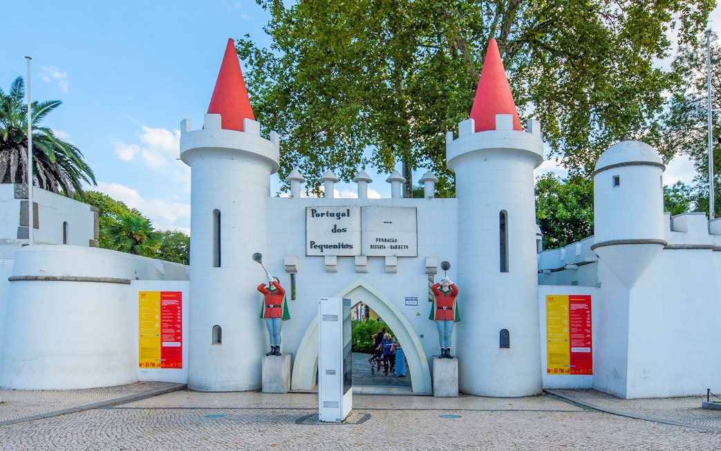 Entrance gate of Portugal dos Pequenitos with white towers and red conical roofs.