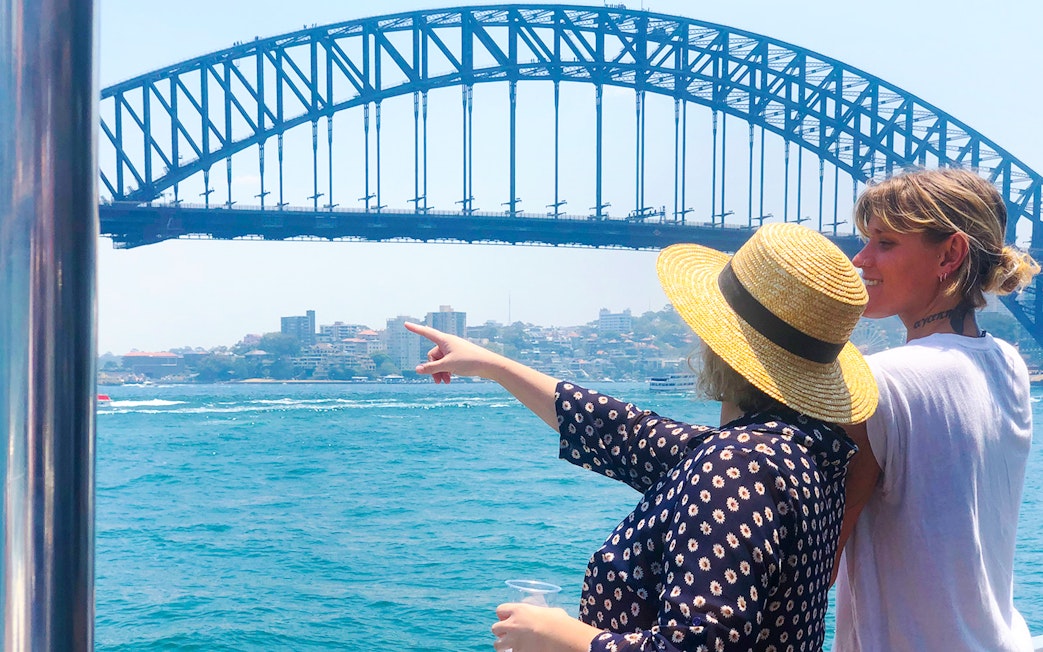 Two people enjoying a view of the Sydney Harbour Bridge from a sightseeing cruise.