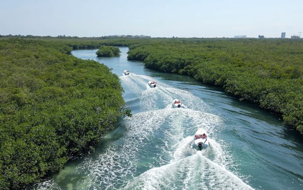 Speedboats navigating through mangroves in Cancun during a snorkel adventure.