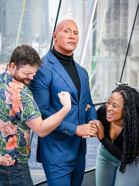 Couple posing with Dwayne Johnson wax figure at Madame Tussauds, New York.