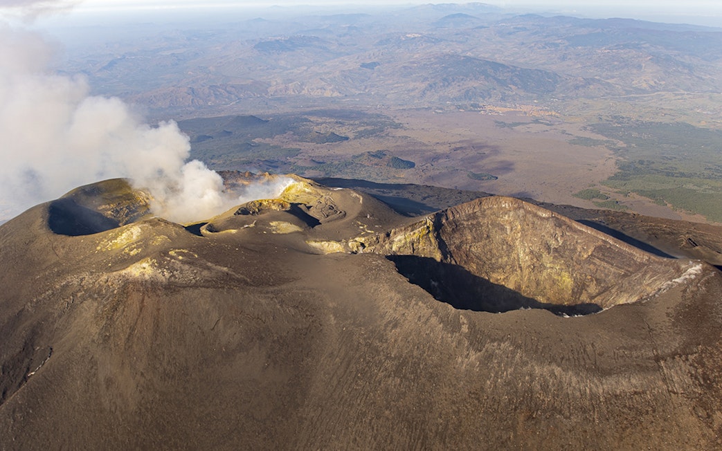 Aerial view of Mount Etna's craters with smoke rising, Sicily, Italy.