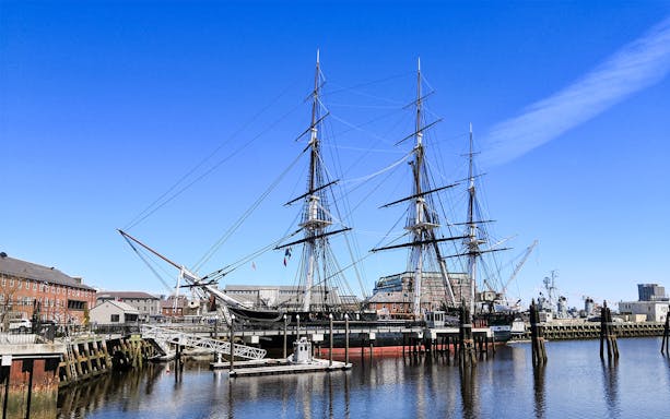 USS Constitution docked at Boston Navy Yard on a sunny day.
