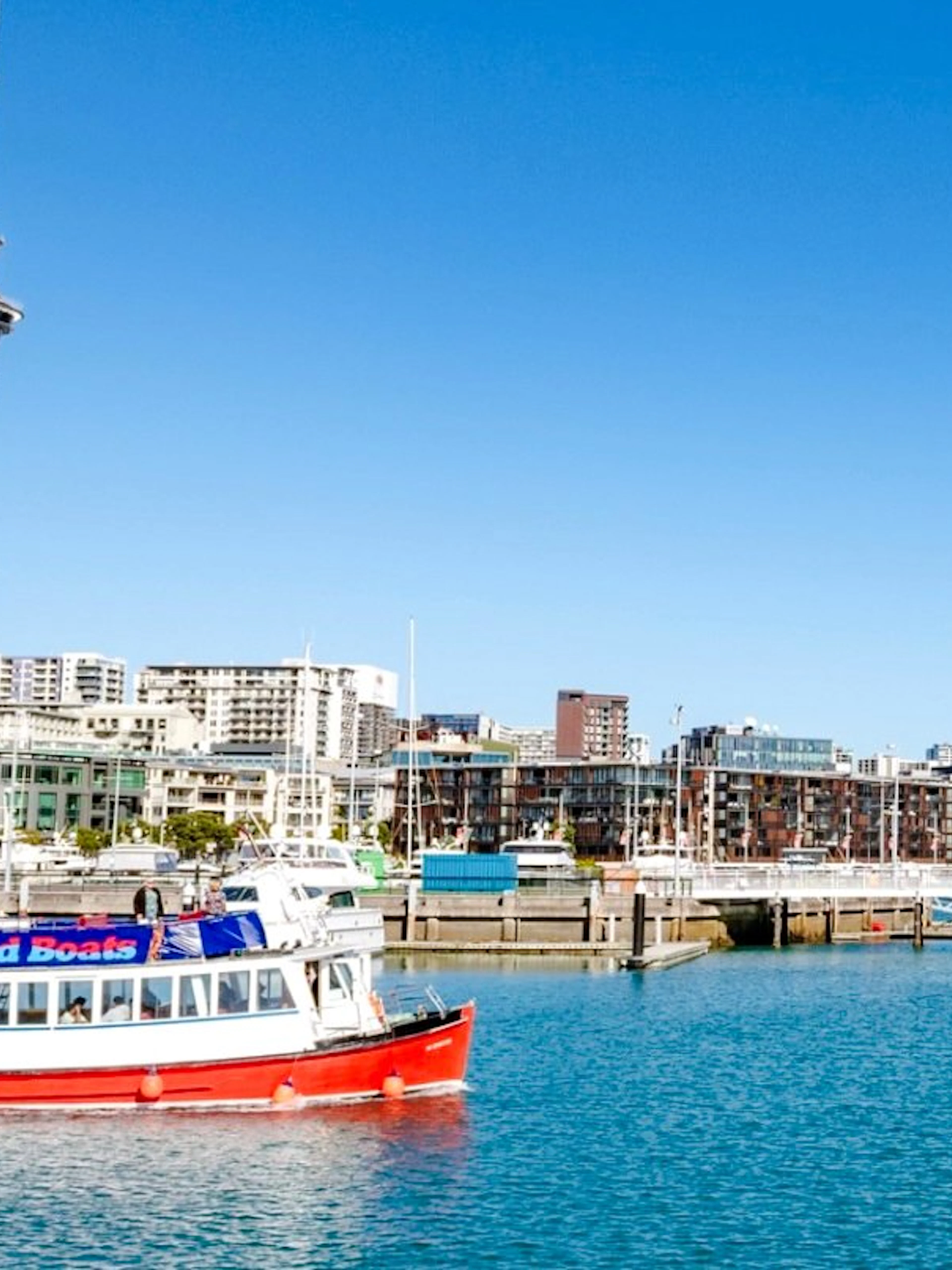 Auckland harbour cruise boat with city skyline and Sky Tower in the background.