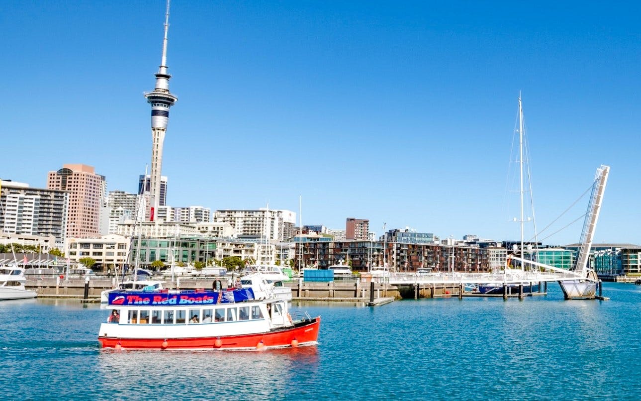 Auckland harbour cruise boat with city skyline and Sky Tower in the background.