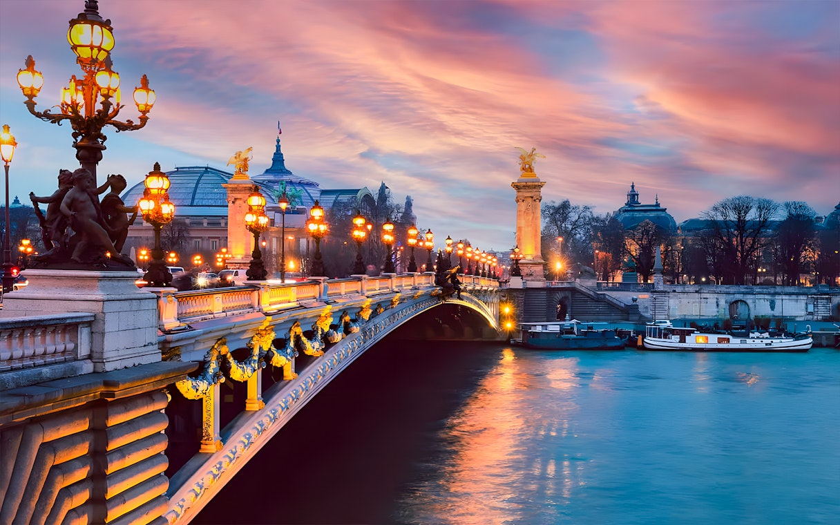 Pont Alexandre III at sunset with boats on the Seine River, Paris.