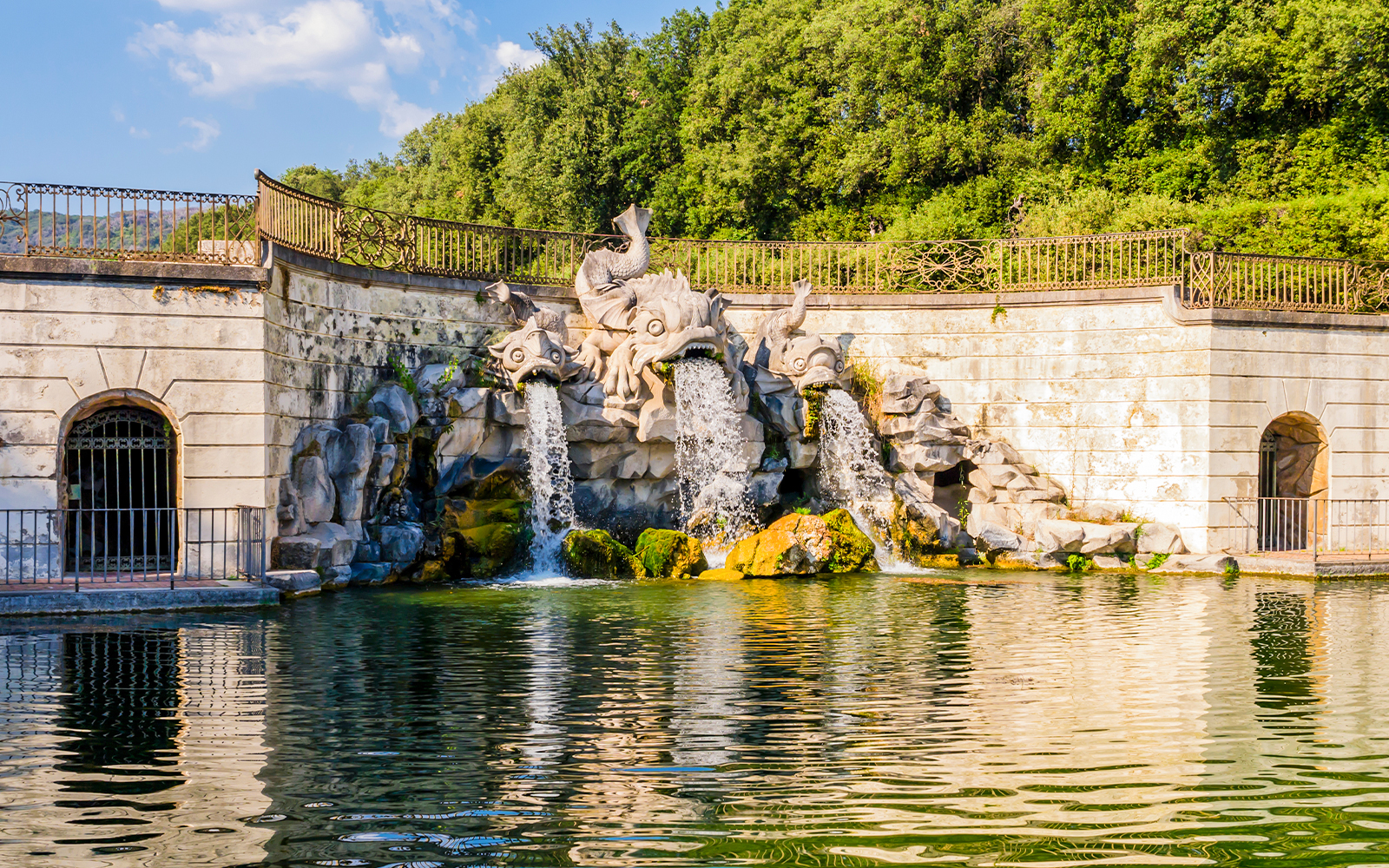Three dolphins fountain at Royal Palace of Caserta with water flowing into a pond.