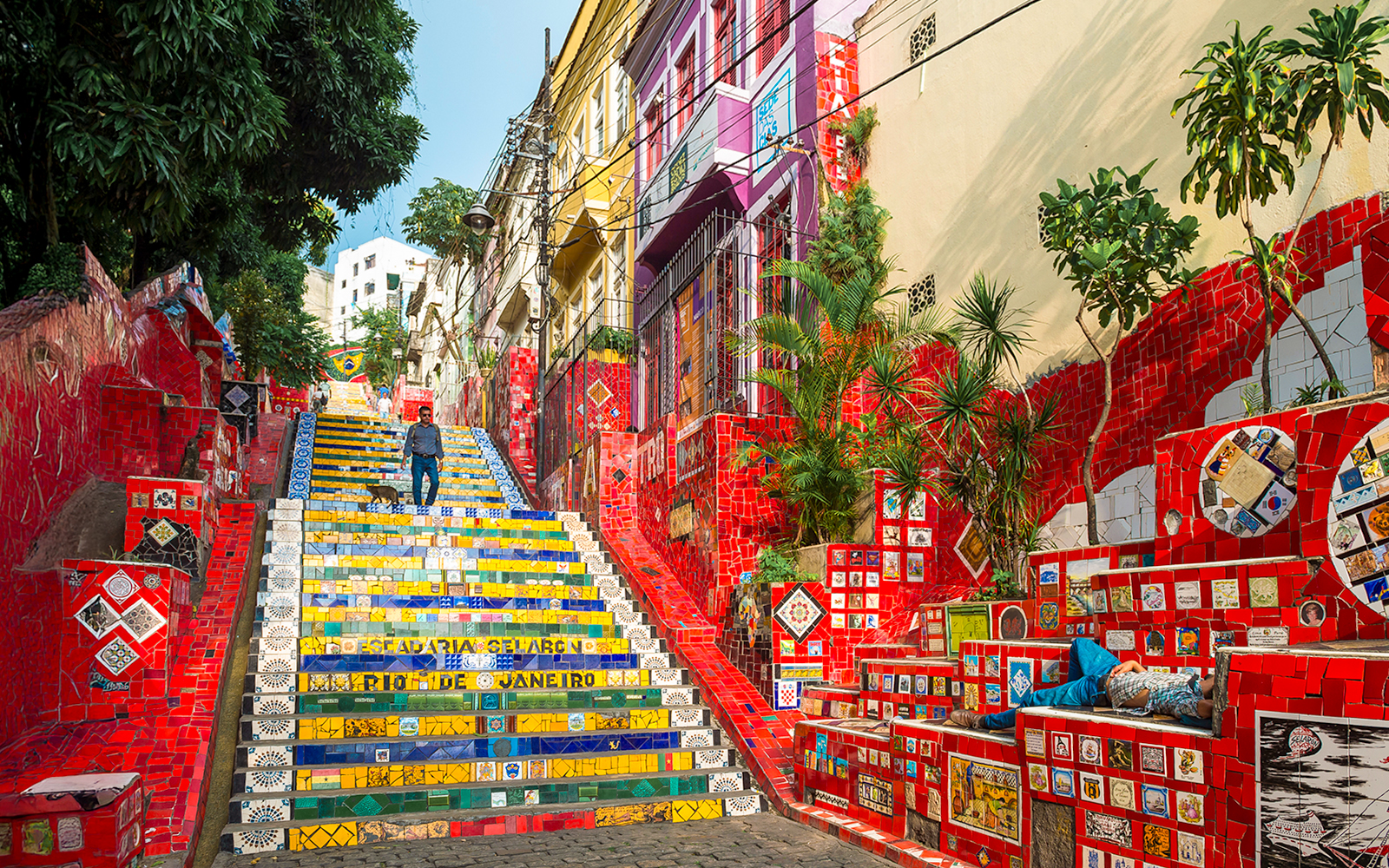 Escadaria Selarón in Rio de Janeiro with colorful mosaic tiles and a person walking.