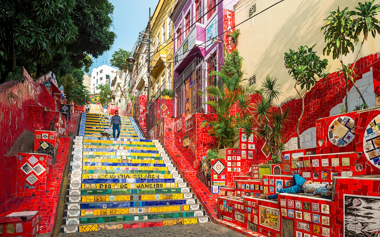 Escadaria Selarón in Rio de Janeiro with colorful mosaic tiles and a person walking.