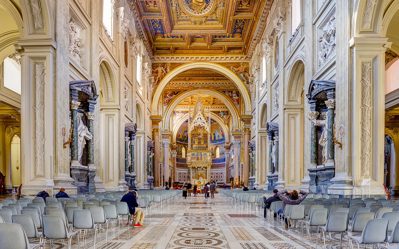 Interior view of the Basilica of Saint John in Lateran with ornate ceiling and statues.