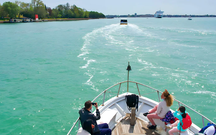 Boat passengers enjoying a scenic ride towards Venice, Italy.
