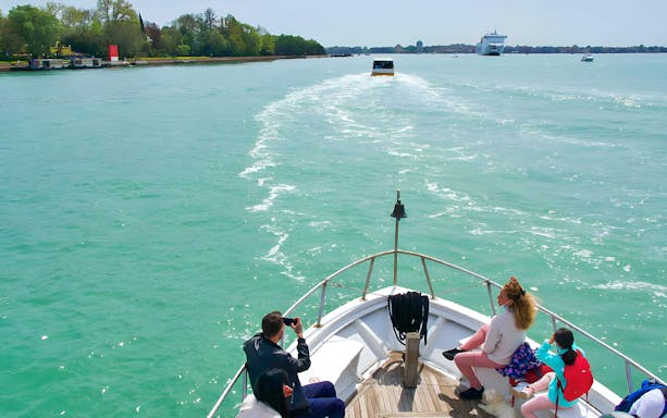 Boat passengers enjoying a scenic ride towards Venice, Italy.