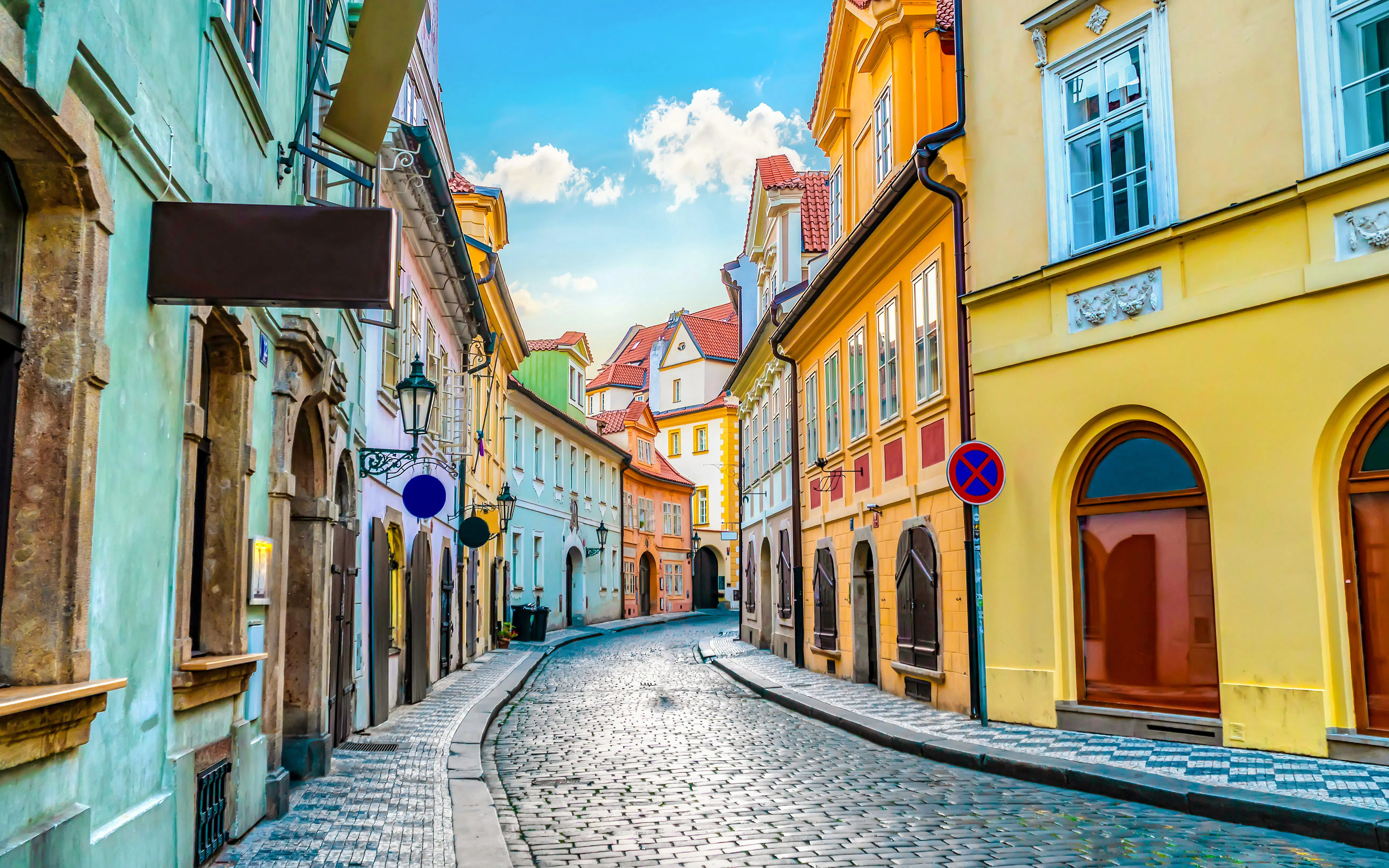 Cobblestone street lined with colorful historic buildings in Prague Old Town.