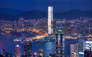 Hong Kong skyline at night viewed from TurboJET Ferry, with illuminated skyscrapers.