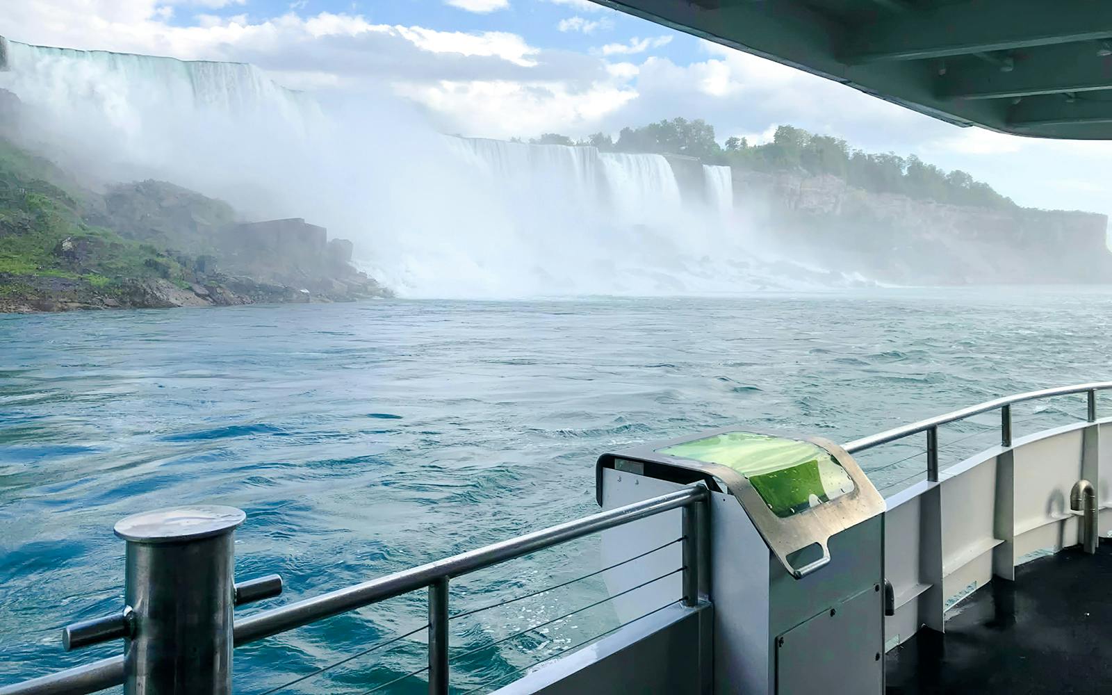 Boat view approaching Niagara Falls USA with mist and cascading water.