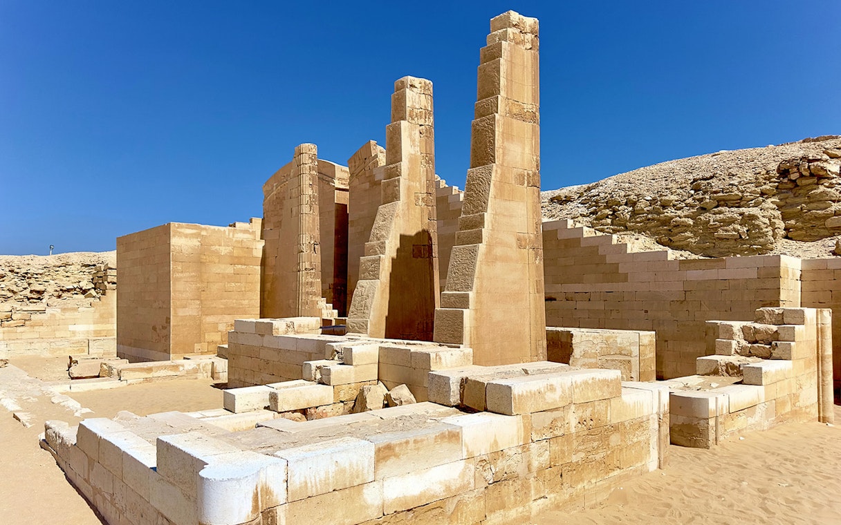 Ancient ruins of a temple in Memphis, Egypt, with stone columns and desert backdrop.