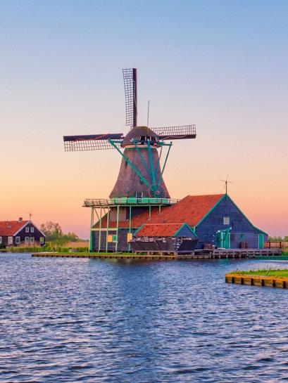 Zaanse Schans windmill by the water at sunset in the Netherlands.