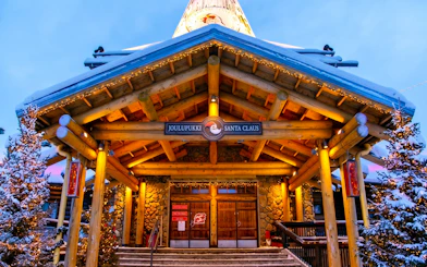 Santa Claus Village entrance with snow-covered roof and festive lights, Rovaniemi.