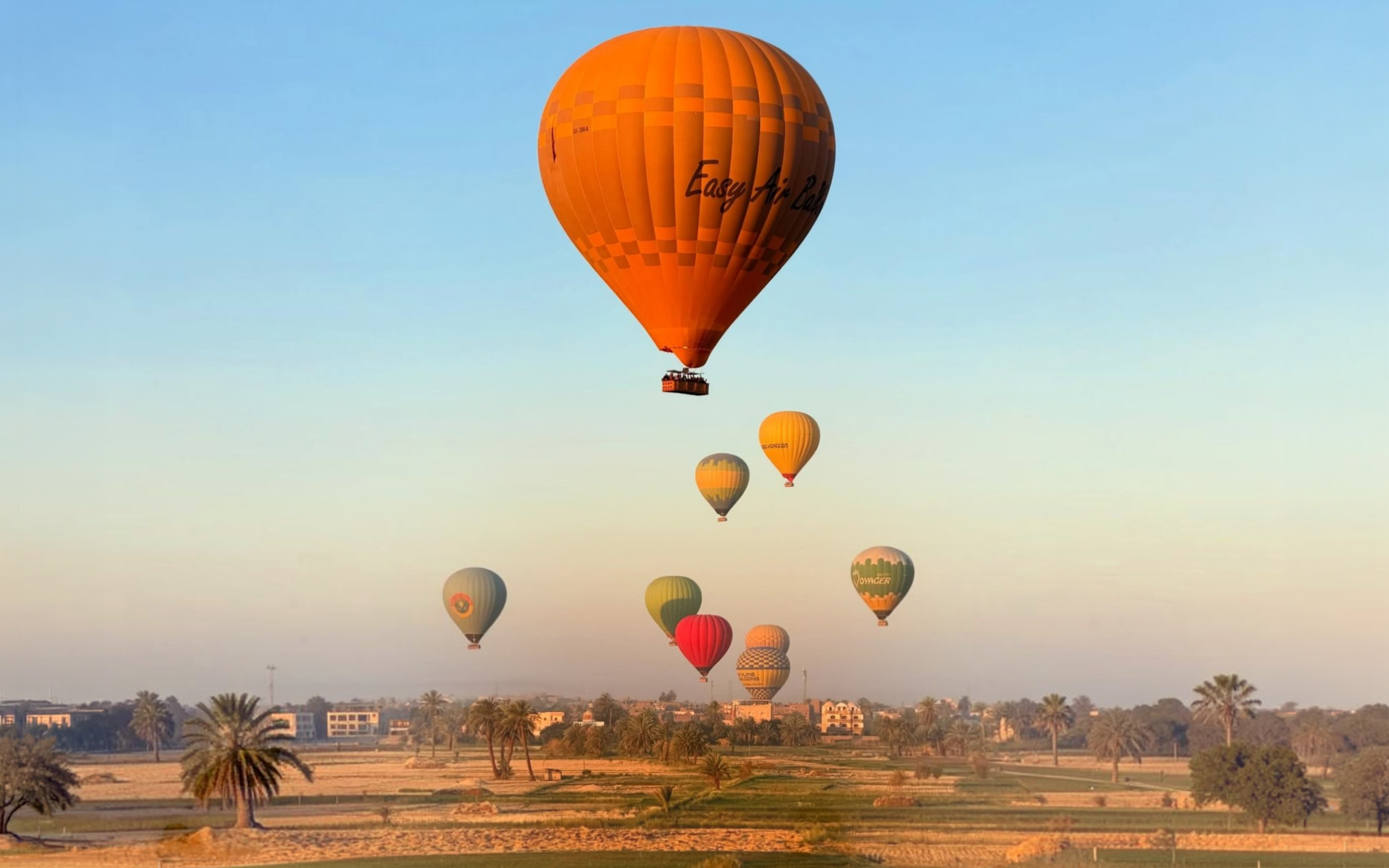 Hot air balloons over Luxor landscape at sunrise.