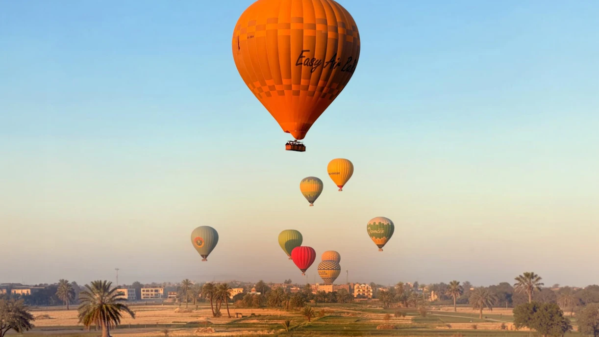 Hot air balloons over Luxor landscape at sunrise.