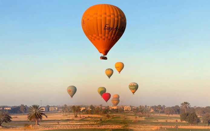 Hot air balloons over Luxor landscape at sunrise.