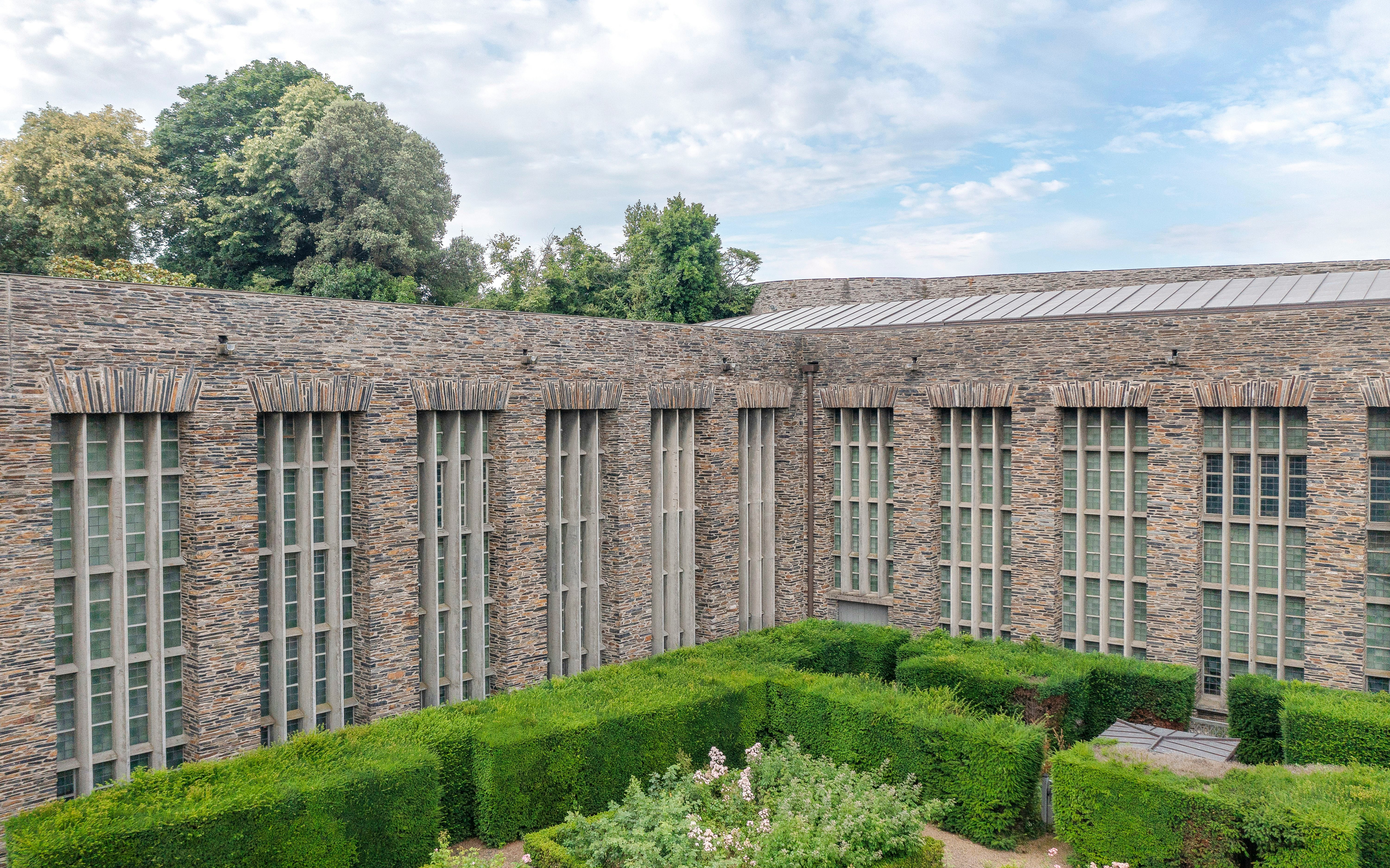 Château d’Angers stone facade with tall windows and manicured hedges.