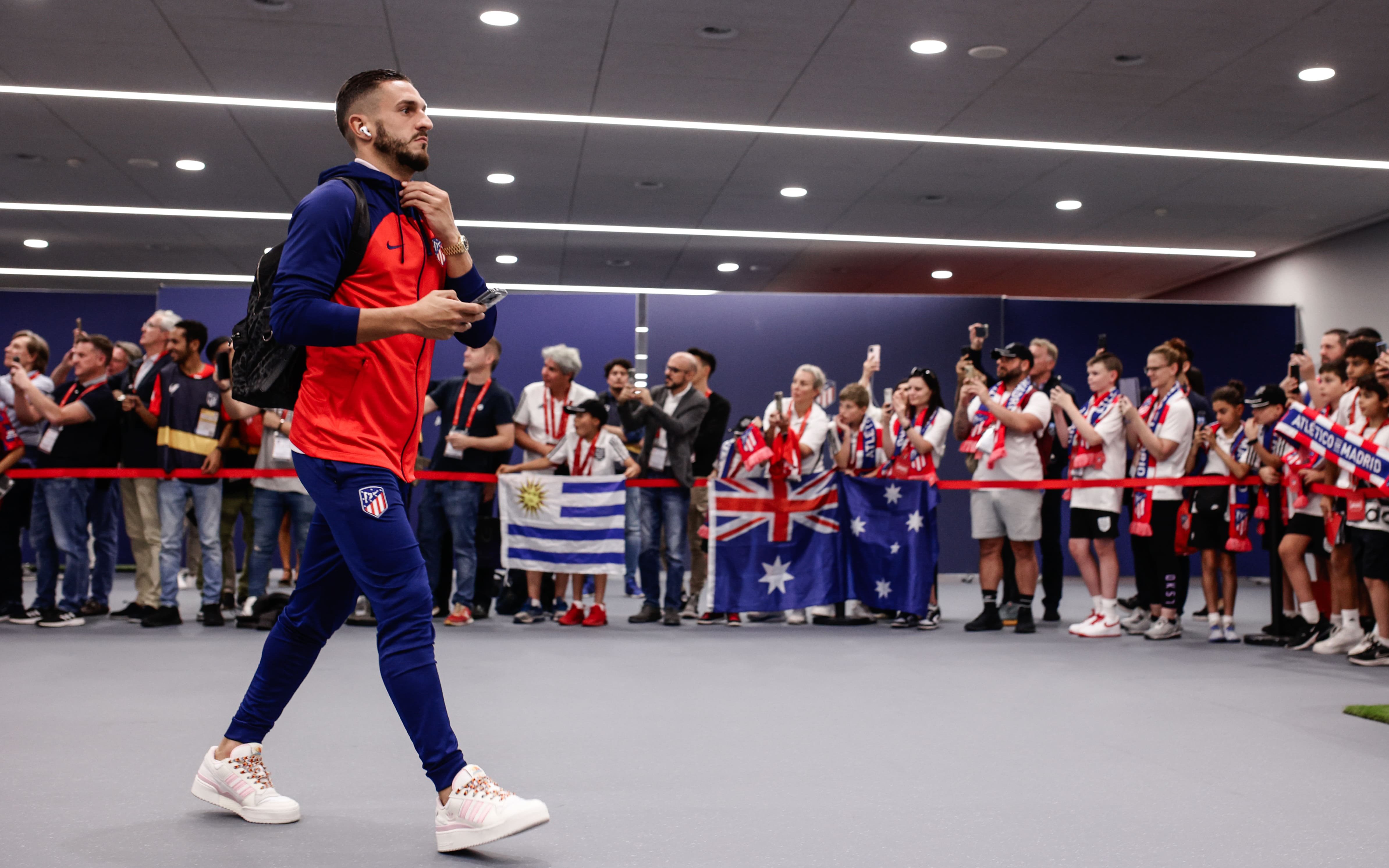 Atlético de Madrid player arrives, greeted by fans with flags and team scarves.