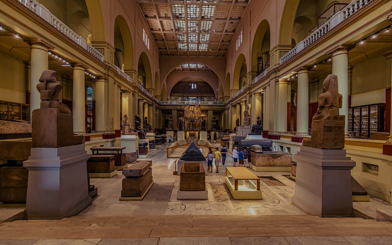 Grand Egyptian Museum interior with ancient statues and visitors exploring exhibits.