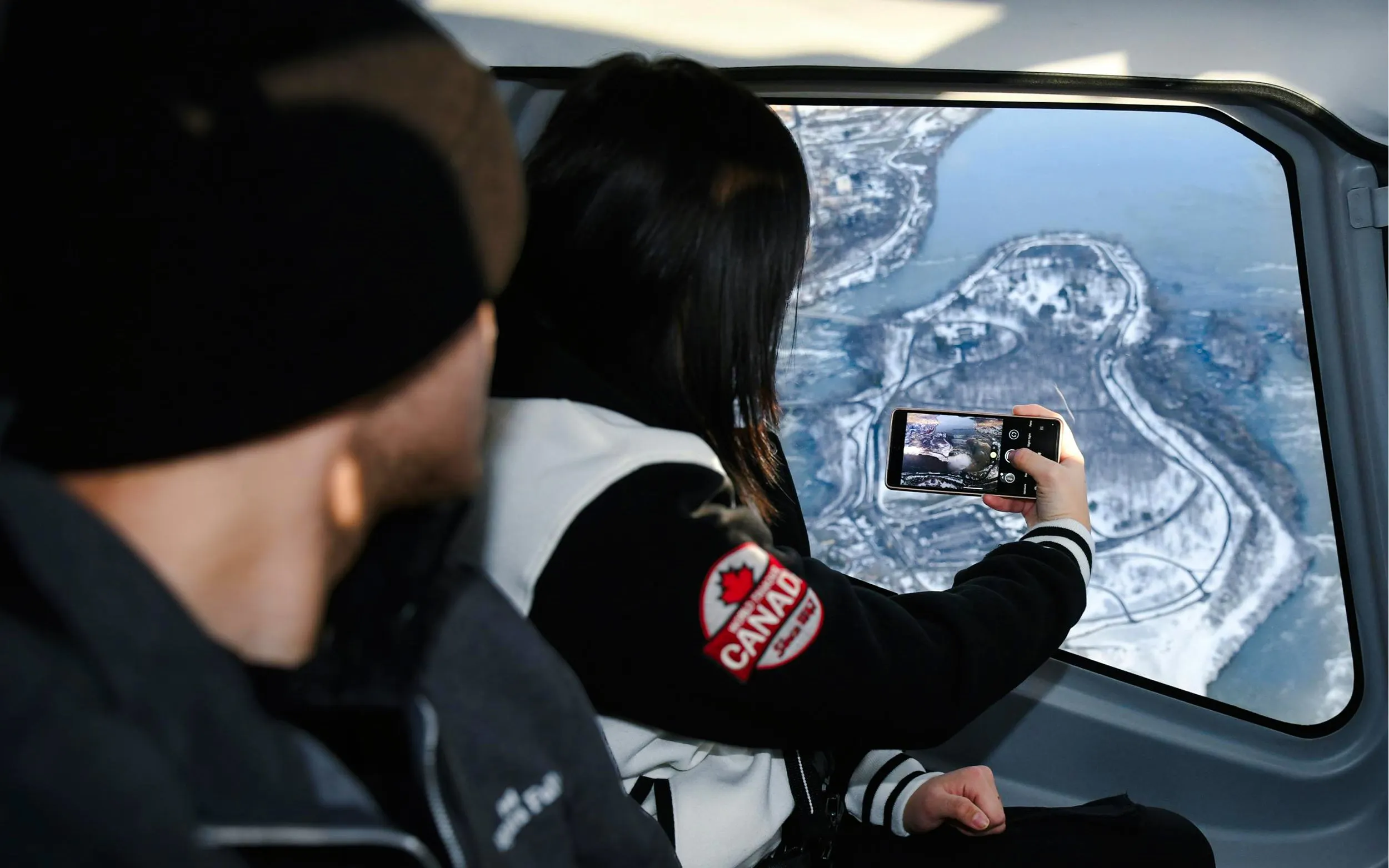 Helicopter view of Niagara Falls, Canada, with passengers capturing the scene.