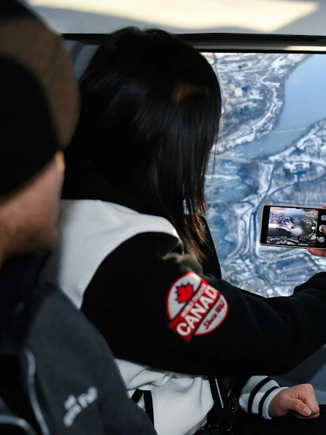 Helicopter view of Niagara Falls, Canada, with passengers capturing the scene.