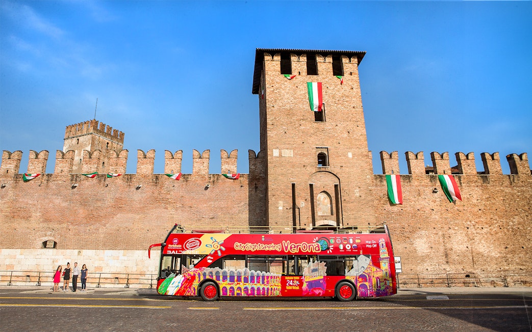 Verona sightseeing bus in front of Castelvecchio on a sunny day.
