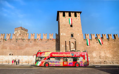 Verona sightseeing bus in front of Castelvecchio on a sunny day.